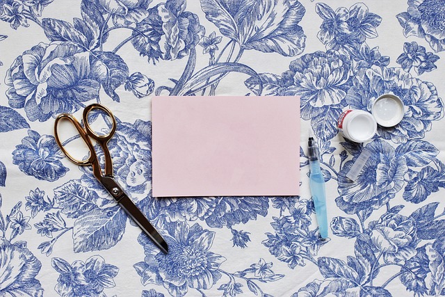 Twelve inch paper trimmer in cream and copper with a swing-out measuring arm extended, a printed inch grid on the base and a 12x12 patterned sheet aligned under the blade rail